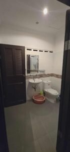 Bathroom with toilet, wall-mounted sink, mirror cabinet, and tiled walls Caption Description