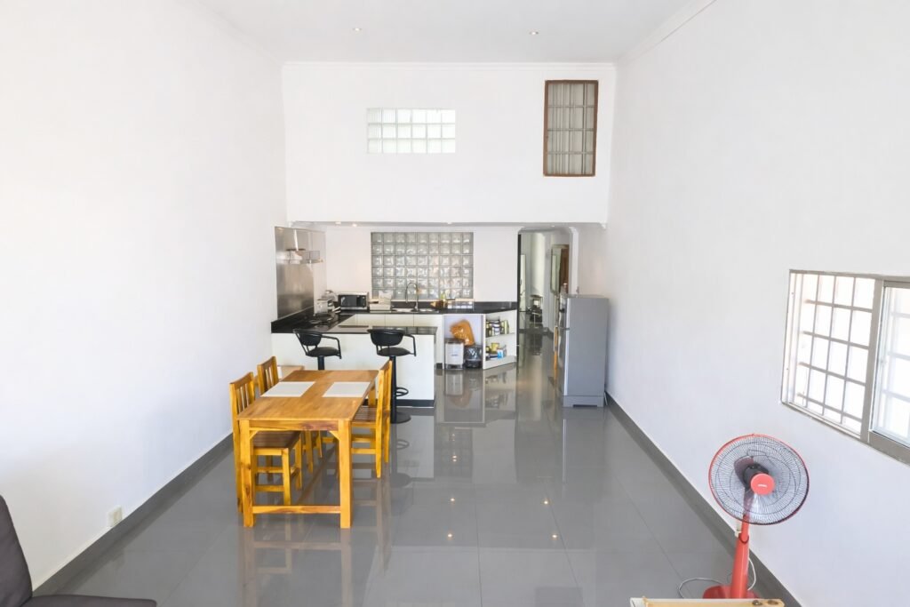 Bright open-plan living and dining area with high ceiling and modern kitchen in a Phnom Penh loft apartment