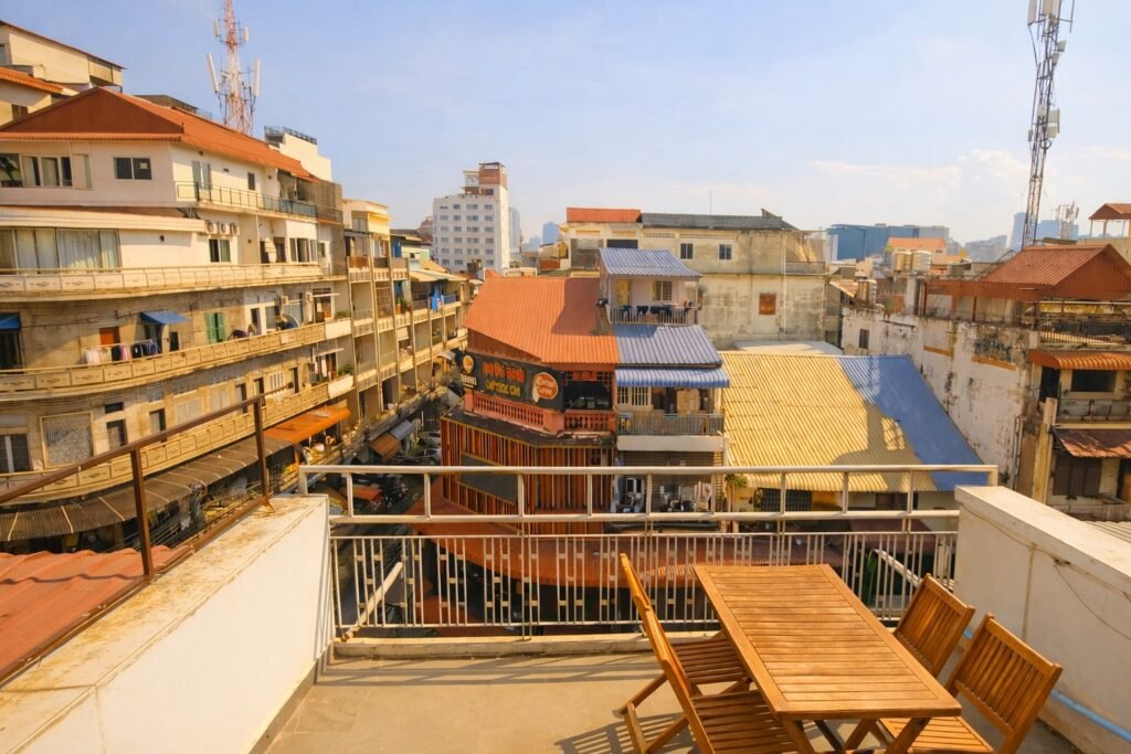 Sunny city view from a private balcony in central Phnom Penh with wooden outdoor table and surrounding buildings