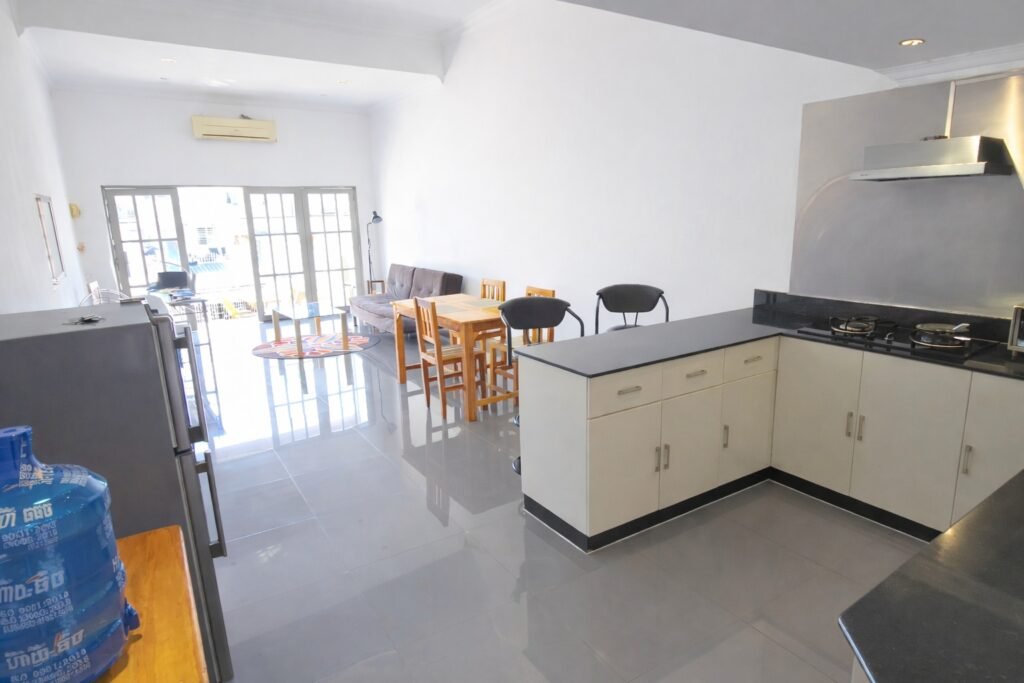 Bright open-plan living, dining, and kitchen area of the Phnom Penh loft apartment with sunlight reflecting on tiled floors
